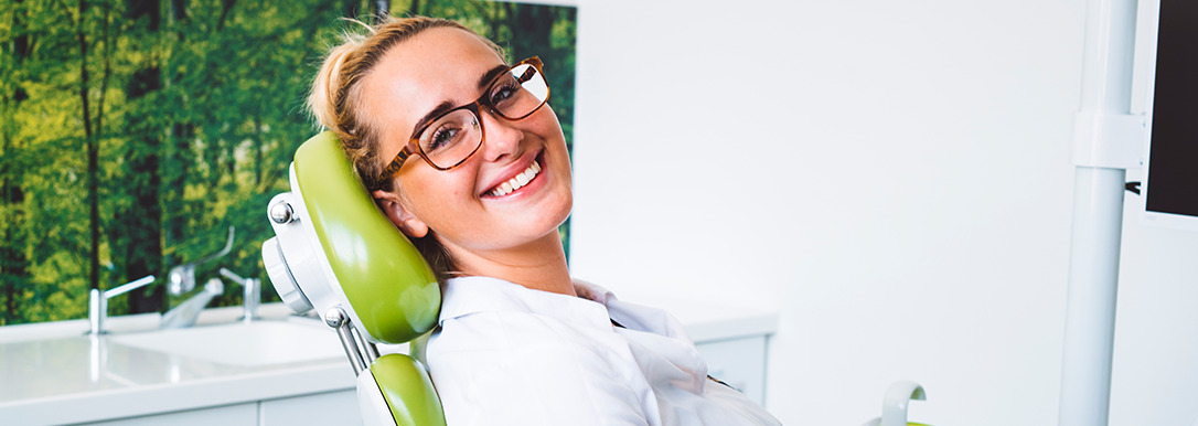 woman smiling while sitting in dentist chair