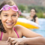 child in braces in summer in a swimming pool