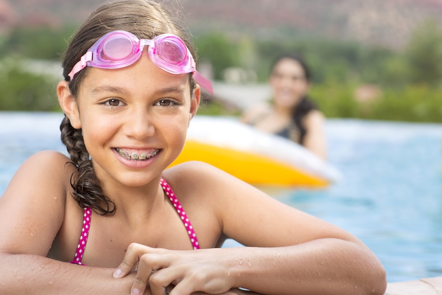child in braces in summer in a swimming pool